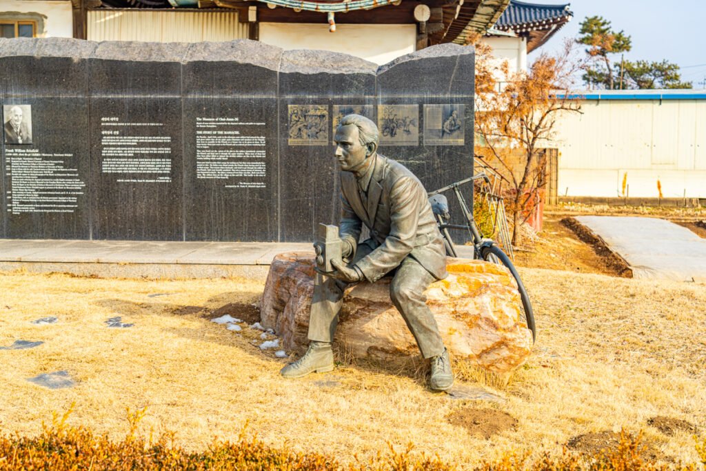 Bronze statue of Dr. Frank W. Schofield at the Hwaseong Independence Movement Memorial, late afternoon light on historical monument